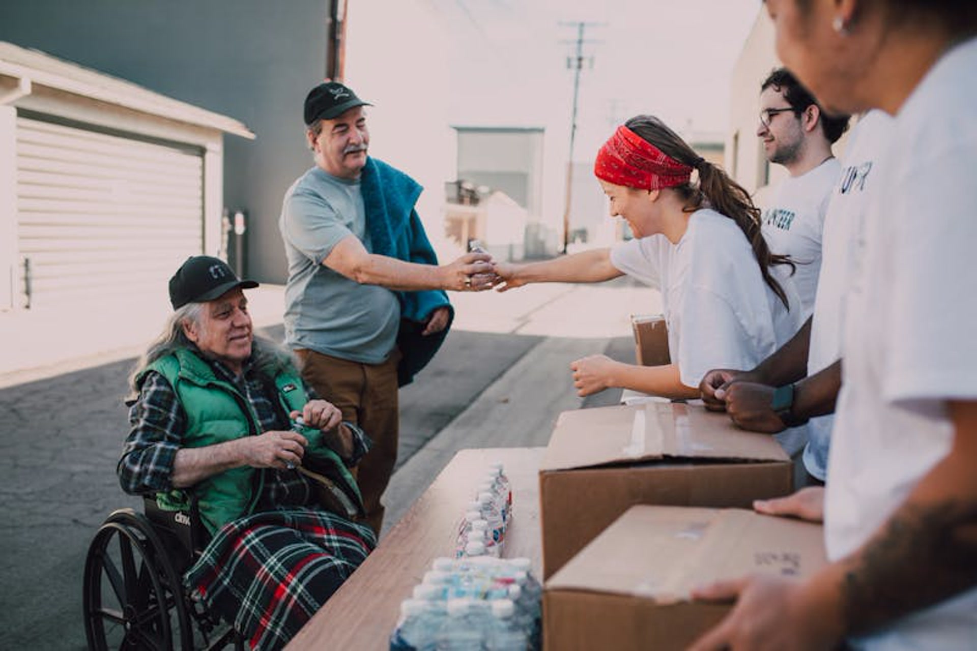 Person with disability actively participating in a community volunteer event, handing out supplies with a smile